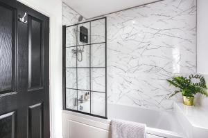 a bathroom with a tub and a marble wall at Urban Retreat with Park Views in Derby