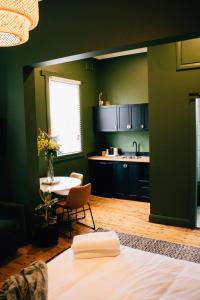 a room with a table and a kitchen with green walls at Rooms of Renown - The Gilded Globe in Leeton