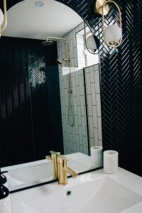 a bathroom with a sink with a mirror and a shower at Rooms of Renown - The Gilded Globe in Leeton