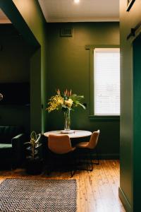 a dining room with a table and a vase of flowers at Rooms of Renown - The Gilded Globe in Leeton