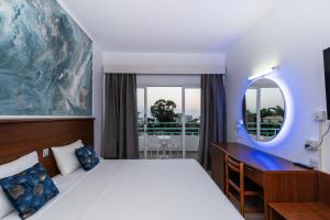 1 dormitorio con cama, escritorio y espejo en Adelais Bay Hotel, en Protaras