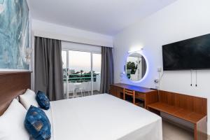 a hotel room with a bed and a desk and a window at Adelais Bay Hotel in Protaras