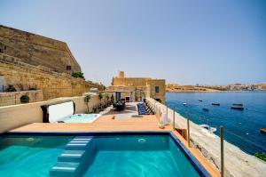 a swimming pool on a deck next to the water at Valletta Waterfront Villa with Pool and Jacuzzi in Valletta