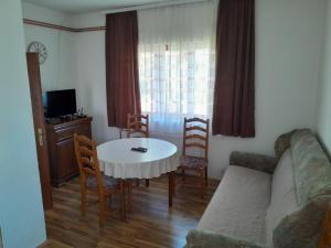 a living room with a couch and a table and chairs at Guest house Kolasin in Kolašin
