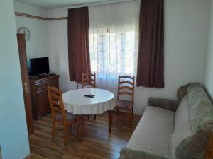 Una sala de estar con un sofá, una mesa y sillas. en Guest house Kolasin, en Kolašin
