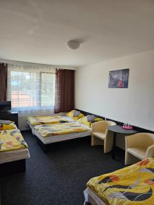 een kamer met 3 bedden en stoelen en een raam bij Hotel Buly in Písek