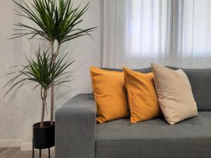 Un sofá gris con almohadas y dos palmeras. en Victoria Flat F&M Moderno, acogedor y céntrico en Málaga