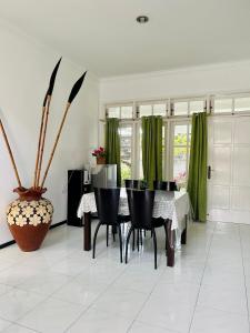 Villa Dedaun Batu في باتو: غرفة طعام مع طاولة وستائر خضراء