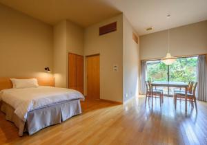 a bedroom with a bed and a table with chairs at Kawatana Grand Hotel Otafuku in Shimonoseki