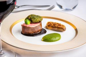 a plate with a piece of meat and a pickle on a table at Langdale Chase Hotel in Windermere