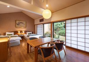 a room with two beds and a table and chairs at Kawatana Grand Hotel Otafuku in Shimonoseki
