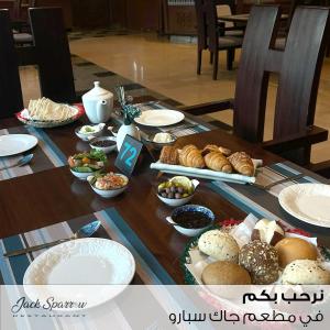 a wooden table with plates of food on it at Majestic Hotel in Manama