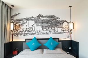 昆明市にあるGongxili - Pujian Hotelのベッド(青い枕、壁にドローイング付)