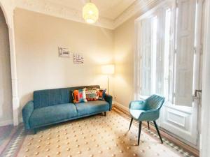 a living room with a blue couch and a chair at By Plaza Catalunya Rooms in Barcelona