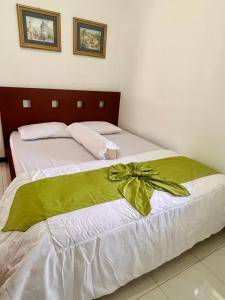 a bed with a green bow on top of it at Villa Dedaun Batu in Batu