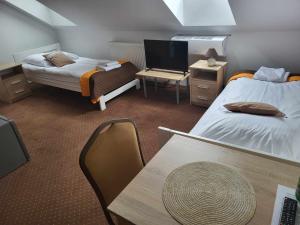 a room with two beds and a table and a tv at Zajazd Promyk in Połaniec