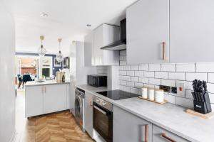 a kitchen with white cabinets and a washer and dryer at Sleek Stylish House 2 Parking - Hot tub & Arcade in Bristol