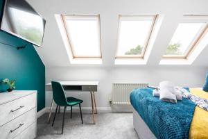 a bedroom with a bed and a desk and windows at Sleek Stylish House 2 Parking - Hot tub & Arcade in Bristol