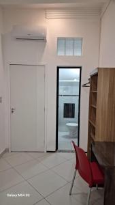 um quarto branco com uma porta e uma cadeira vermelha em SUITE STAR em Pau dos Ferros