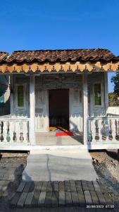 ein weißes Gebäude mit einer Veranda mit einem Dach in der Unterkunft Omah Kayu Palagan in Ngaglik + 8 Fotos