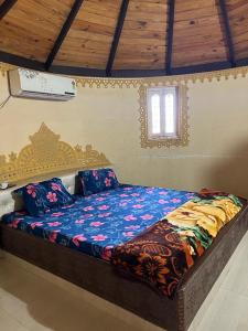 a bedroom with a bed with a blue comforter and a window at The Kutch House in Bhuj