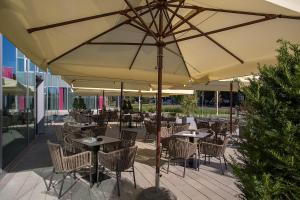 eine Terrasse mit Tischen und Stühlen unter einem Sonnenschirm in der Unterkunft Hilton Garden Inn Zagreb - Radnička in Zagreb