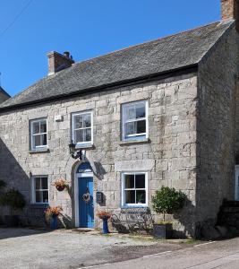 un edificio de piedra con una puerta y ventanas azules en Britannia House Vintage B&B Cornwall, en Helston