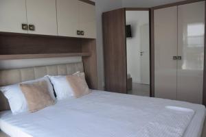 1 dormitorio con 1 cama grande con sábanas y almohadas blancas en Real Residence -apartament cu 3 camere- Valeni 144, en Ploieşti