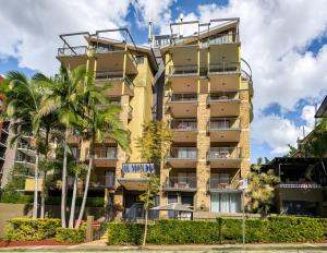 a tall yellow building with palm trees in front of it at Il Mondo Boutique Hotel in Brisbane