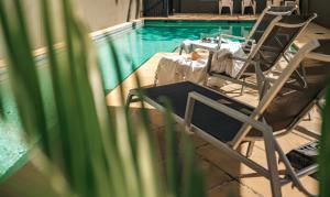 two chairs and a table next to a swimming pool at Il Mondo Boutique Hotel in Brisbane