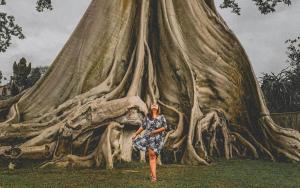 a woman standing in front of a large tree at Alam Desa Homestay by AGATA in Perean