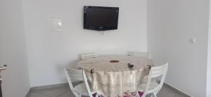 a table with white chairs and a tv on a wall at Séjour Paisible au Bord de la Nature. in Tangier