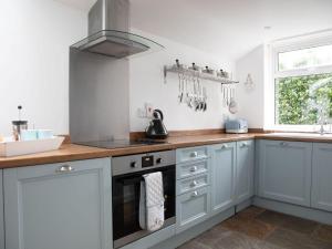 a kitchen with white cabinets and a stove top oven at Foxbear in Kingsbridge