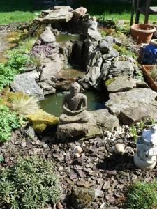 un jardin avec une statue d'un buddha dans un étang dans l'établissement Ferienwohnung Schanbacher, à Beerfelden