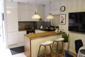 a kitchen with white cabinets and a counter with stools at Apartament Euro 2 Kraków in Krakow