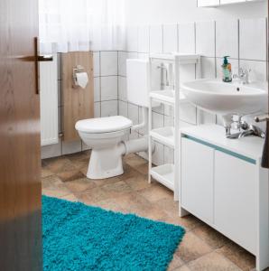 y baño con aseo, lavabo y alfombra azul. en Ferienwohnung Kirschblüte 