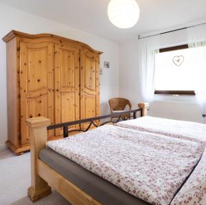 1 dormitorio con 1 cama, armario de madera y ventana en Ferienwohnung Kirschblüte 