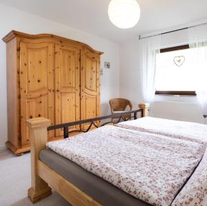 a bedroom with a bed and a wooden cabinet and a window at 2 Bett Ferienwohnung Kirschblüte in Wengenroth