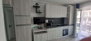 a kitchen with white cabinets and a sink and a microwave at Garsoniera Saturn in Saturn