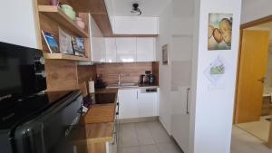 a small kitchen with white cabinets and a sink at Riella Home in Szombathely