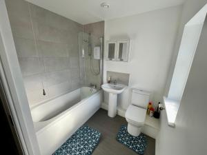 a bathroom with a white tub and a toilet and a sink at Silver Stag Properties, 3 BR House in Ashby in Ashby de la Zouch