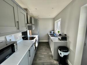 a kitchen with white cabinets and a sink and a counter at Comfortable 3-BR Home Great Location in Ashby in Ashby de la Zouch +9 photos