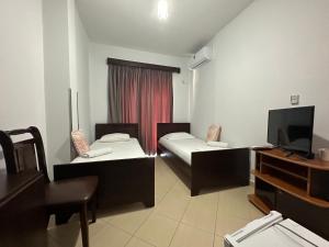 a small room with two beds and a television at Hotel Trifoni in Përmet