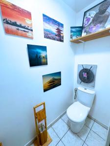 a bathroom with a toilet and pictures on the wall at Passion et détente by UTA HOUSE in Saint-Denis