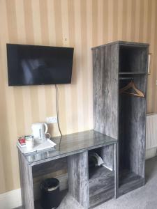 een houten bureau met een tv aan de muur bij Alexander Guest House in Edinburgh