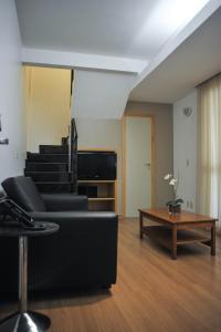 a living room with a black couch and a table at San Diego Suítes Lourdes - OFICIAL in Belo Horizonte