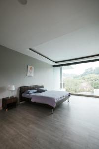 ein Schlafzimmer mit einem Bett und einem großen Fenster in der Unterkunft Tropical Bliss Villa by The Feelas in Bandung