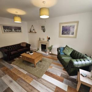 a living room with a leather couch and a table at Sleeps 8 Matlock/ Matlock Bath Pet Friendly in Matlock Bank