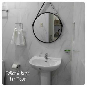 bagno bianco con lavandino e specchio di 80Square Guest House a Gingoog