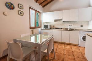 フィレンツェにあるSan Frediano Houseの白いキャビネット、テーブルと椅子付きのキッチンが備わります。